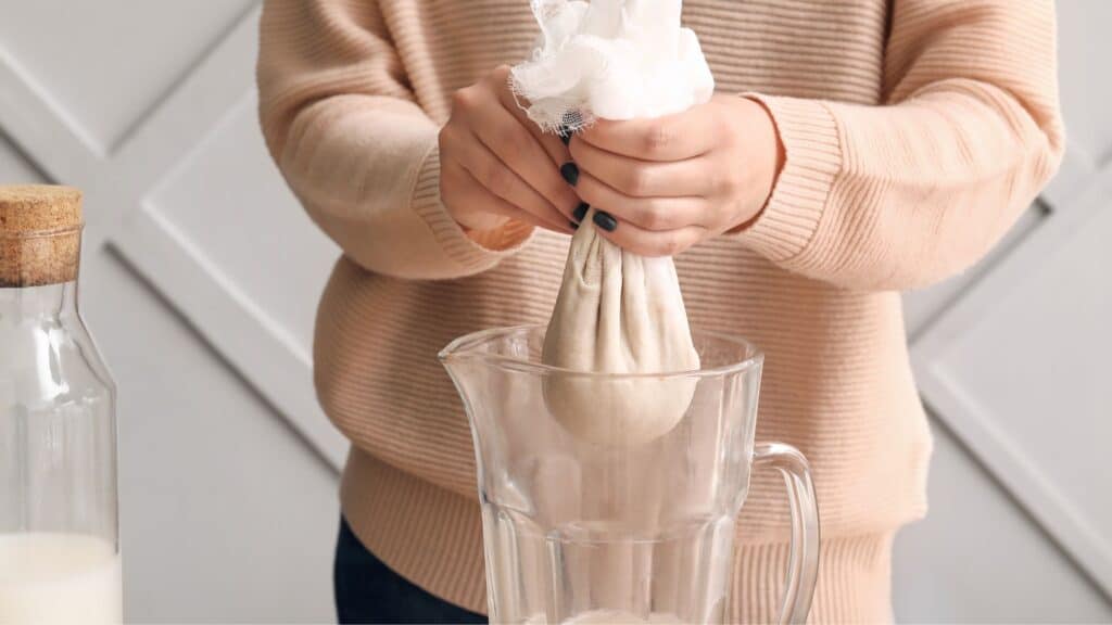 woman squeezing oat milk on kitchen table close up